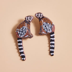 Brown, Black, White, and Grey Beaded and Embroidered Lemur Stud Earrings on Tan Background